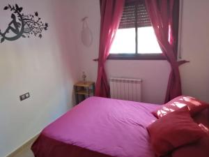 een slaapkamer met een bed met roze lakens en een raam bij APARTAMENTOSTACRISTINA in Santa Cristina d'Aro