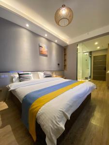 um quarto com uma cama grande e um cobertor amarelo e azul em Qingdao Shuiyunjian Apartment em Qingdao