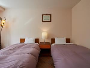 a room with two beds and a lamp on a table at Asama Kogen Hotel in Tsumagoi