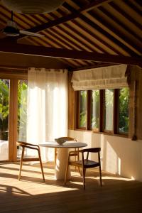 a table and two chairs in a room with windows at Modjo Apartment Bingin in Uluwatu