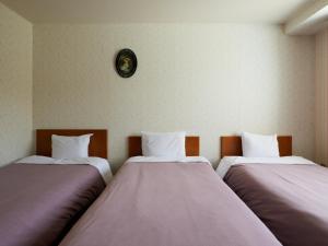 2 letti in una camera con orologio a parete di Asama Kogen Hotel a Tsumagoi