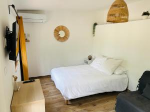 sypialnia z białym łóżkiem i drewnianą podłogą w obiekcie Le Cabanon w mieście Collobrières