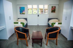 um quarto com duas camas e uma mesa e duas cadeiras em Yatulau Hotel and Conference em Suva