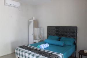 a bedroom with a bed with a black headboard and blue pillows at WL GUESTHOUSE in Labuan Bajo