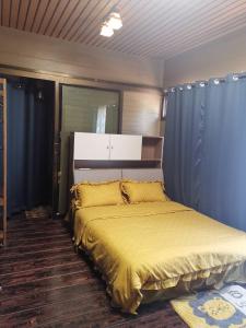 a bedroom with a bed with a yellow bedspread at Mana-An Lake Hill Resort in Chiang Mai