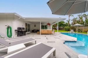 a patio with a swimming pool and an umbrella at Luxury Designer Delray Beach. 10 Min to the Beach! in Delray Beach