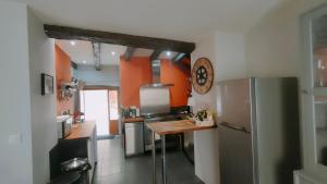 eine Küche mit orangefarbenen Wänden und einem Kühlschrank aus Edelstahl in der Unterkunft Maison Barossa Issigeac in Issigeac