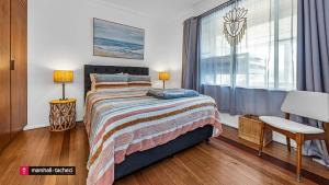 a bedroom with a large bed and a window at Bermagui Breeze Holiday House 5 bedroom 18-20 Mumbulla Street - Bermagui in Bermagui