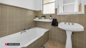 a bathroom with a white tub and a sink at Bermagui Breeze Holiday House 5 bedroom 18-20 Mumbulla Street - Bermagui in Bermagui +20 photos