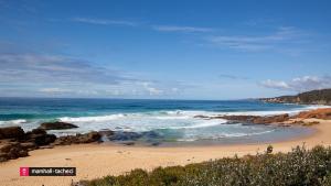 a beach with rocks and the ocean on a sunny day at Bermagui Breeze Holiday House 5 bedroom 18-20 Mumbulla Street - Bermagui in Bermagui