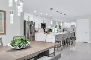 a white kitchen with a table and chairs and a counter at Luxury Designer Delray Beach. 10 Min to the Beach! in Delray Beach