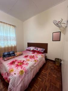 a bedroom with a bed with pink flowers on it at D'Puncak Arabella Muslim Homestay in Cameron Highlands