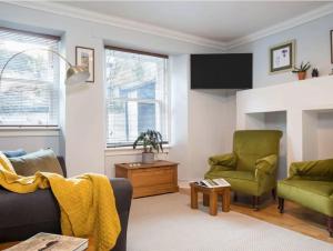 uma sala de estar com duas cadeiras verdes e uma televisão em The Third em Edinburgo