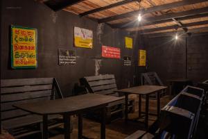 two tables and chairs in a restaurant with signs on the wall at Deck on the hills Bunks in Kandy