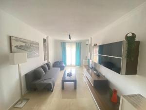 ein Wohnzimmer mit einem Sofa und einem TV in der Unterkunft Fabuloso apartamento en Benalmadena con piscina in Benalmádena