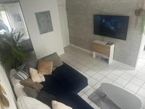 a living room with a couch and a flat screen tv at F2 cocooning centre ville 4 personne in Beaumont-sur-Oise
