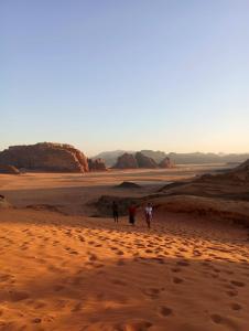 dwoje ludzi spacerujących po pustyni o zachodzie słońca w obiekcie Bedouin experiences w Akabie