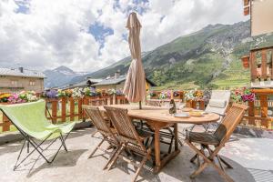 eine Terrasse mit einem Tisch, Stühlen und einem Sonnenschirm in der Unterkunft Locations Berne Milesi in Lanslevillard