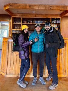 three people standing in front of a bar at Trekker's Lodge 