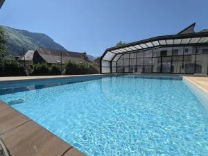 Appartement 4 personnes et jardin في Bielle: مسبح ازرق كبير امام مبنى