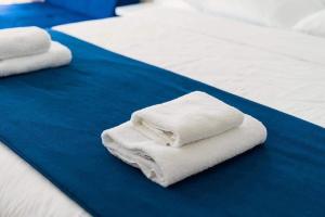 three white towels are stacked on a bed at Orbi City Hotel VIP - Batumi in Batumi