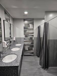 un bagno pubblico con tre lavandini e specchi di Orion Hostel a Yerevan