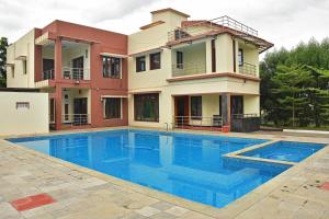 a villa with a swimming pool in front of a house at ART Resort & Farm House in Mahabalipuram