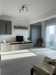 Il comprend un salon blanc doté d'un canapé et d'une télévision. dans l'établissement Luxury Apartments and Studios Boulevard G Enescu Suceava, à Suceava