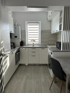 una cucina con armadi bianchi, tavolo e finestra di Luxury Apartments and Studios Boulevard G Enescu Suceava a Suceava