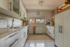 a kitchen with white cabinets and a sink at Vineyard Cottage Hočevar With Sauna - Happy Rentals in Novo Mesto