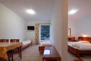 Habitación con 3 camas, mesa y ventana en MIRSINI HOTEL en Plomari