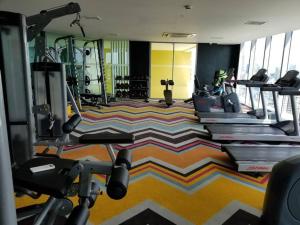 a gym with several treadmills and tread machines at Homey 1BR Acqua Livingstone with Netflix, Pool & Gym in Manila