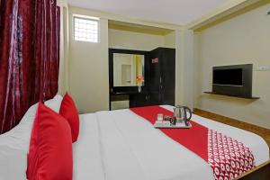 a bedroom with a bed with red pillows and a television at Flagship Honnagiri Residency in Bangalore