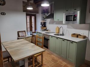 cocina con armarios verdes y mesa de madera en Casa Rural: La casa El cura, en Madrigal de la Vera