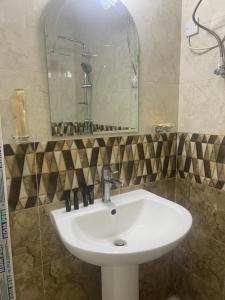 La salle de bains est pourvue d'un lavabo blanc et d'un miroir. dans l'établissement معيذر للشقق المفروشه, à Doha