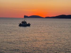 un bateau au milieu de l'océan au coucher du soleil dans l'établissement Panoramic Bastioni Sea View, à Alghero