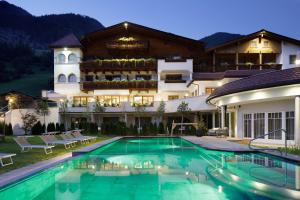 un hotel con piscina di fronte a un edificio di Naturhotel MOLIN a San Giovanni in Val Aurina