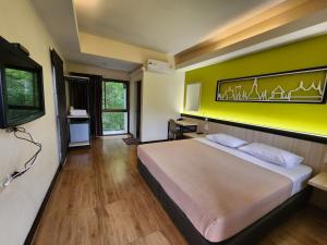 a bedroom with a large bed with a yellow wall at Penpark Place in Bangkok