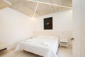 a white bedroom with a bed and a desk at Benaki85 in Ladines