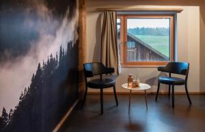 a room with two chairs and a table and a window at Hôtel-Restaurant Le Cochon Rose in La Sagne