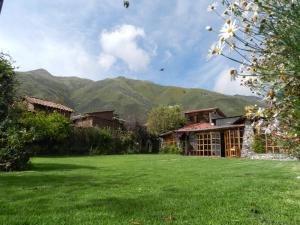 a large yard with a building and mountains in the background at Eco Tampu Andahuaylillas- Hospedaje Ecosostenible in Andalmailillas