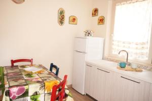 a kitchen with a table and a white refrigerator at Appartamento Il Mandorlo in Capoliveri