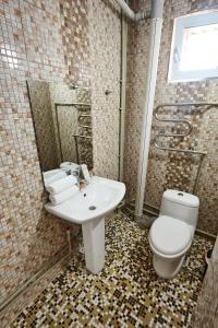 a bathroom with a white toilet and a sink at KZO Hotel in Shymkent