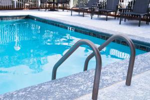 a swimming pool with a metal handrail next to a swimming pool at Fairfield Inn & Suites Atlanta Airport North in Atlanta