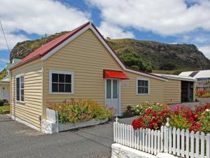 a yellow house with a white fence and flowers at Stanley Holiday Houses in Stanley