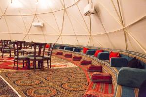 Desert Season Camp في وادي رم: غرفة بها طاولات وكراسي في خيمة