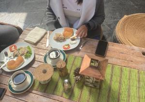 una mujer sentada en una mesa con un plato de comida en Eco Tampu Andahuaylillas- Hospedaje Ecosostenible, en Andahuaylillas