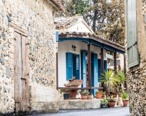 een stenen gebouw met blauwe luiken en potplanten bij Guesthouse Gonia in Pera Orinis