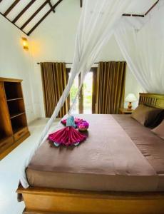 a bedroom with a canopy bed with flowers on it at Puring Bungalows in Gili Air