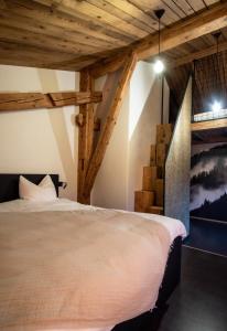 een slaapkamer met een bed in een kamer met houten plafonds bij Hôtel-Restaurant Le Cochon Rose in La Sagne